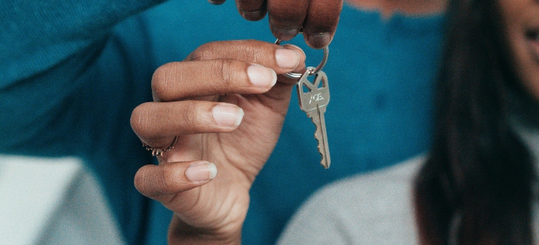 Close-up of hands holding house keys, symbolizing a successful move and starting life in a new home.